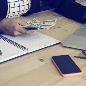 Persona revisando documentos y contando dinero, relacionado con la consulta sobre si se puede cobrar el paro tras haber sido asalariado antes de autónomo.