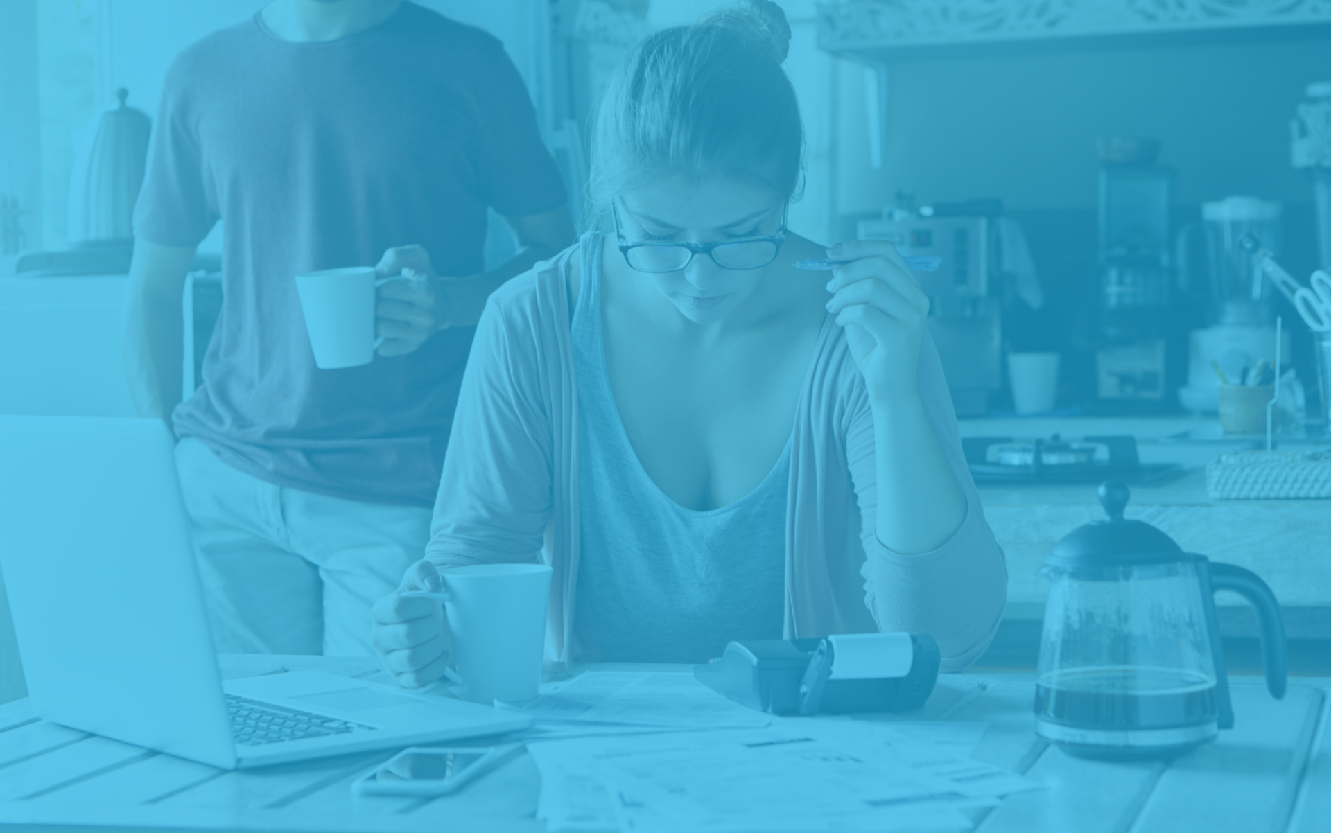 Pareja revisando cuentas con calculadora y portátil en casa, buscando consells perquè les petites societats puguin estalviar en impostos.