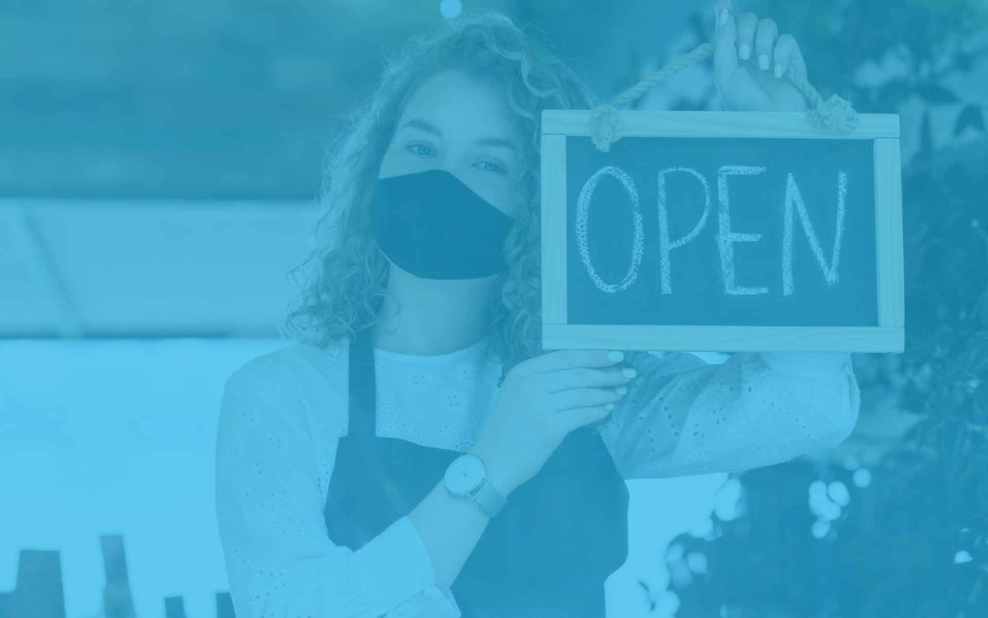 Propietària mostrant un cartell d'‘Open’, representant el procés d’obrir un bar a Espanya