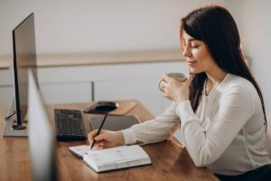 Mujer autónoma trabajando en su oficina, tomando café y organizando su agenda. Hacienda deberá probar el error de los autónomos antes de imponer sanciones por deducciones fiscales.
