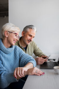 Pareja de autónomos mayores de 65 años revisando su declaración de la renta en un ordenador portátil, con actitud tranquila y positiva.